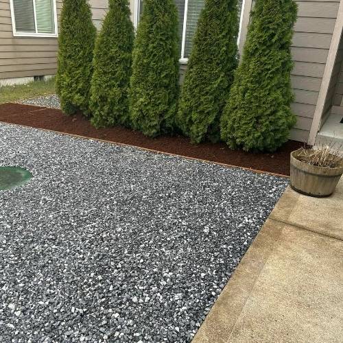 Landscaper trimming shrubs and maintaining garden bed in Kansas City